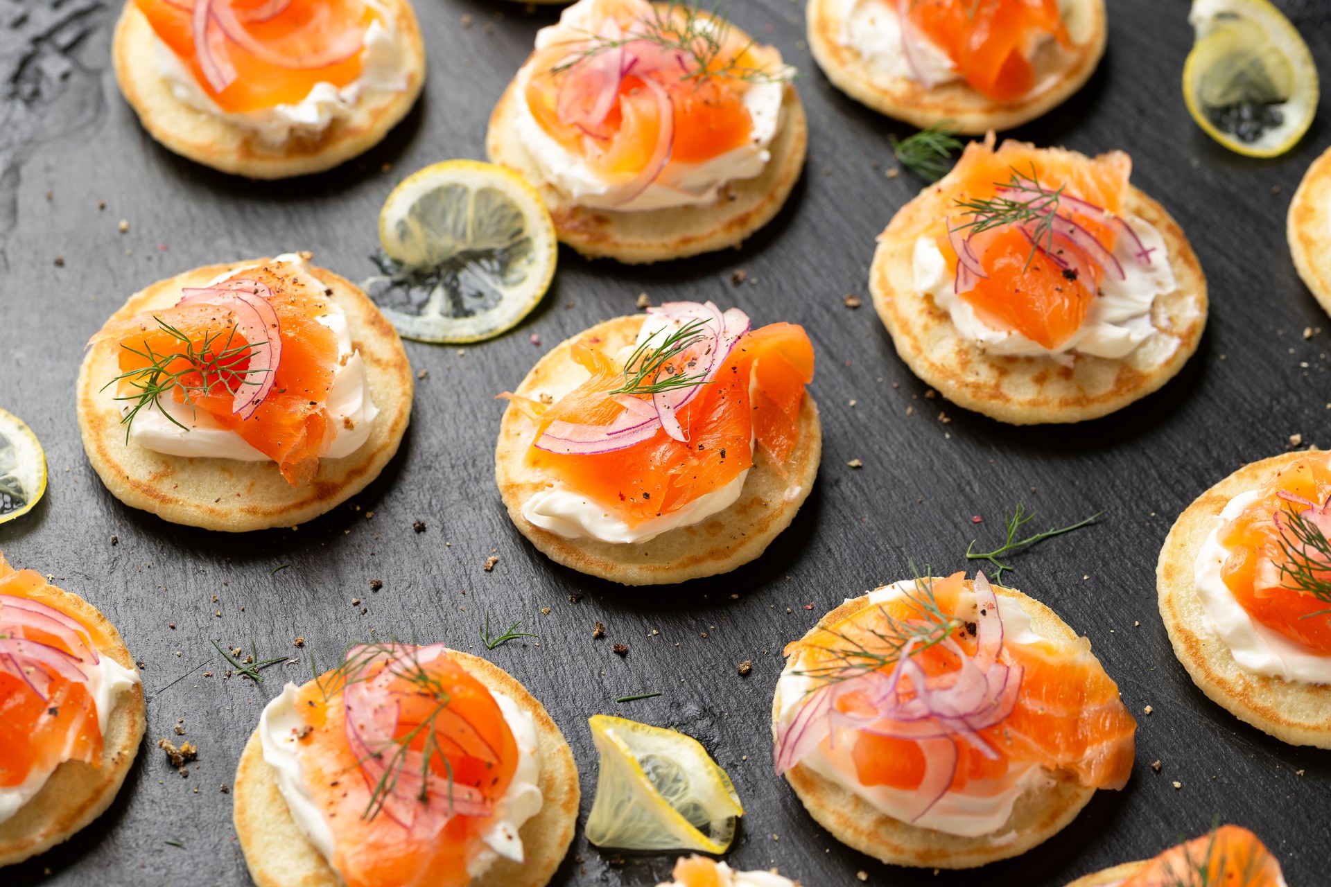 Mini blini pancakes with soft cheese, cold smoked salmon and dill