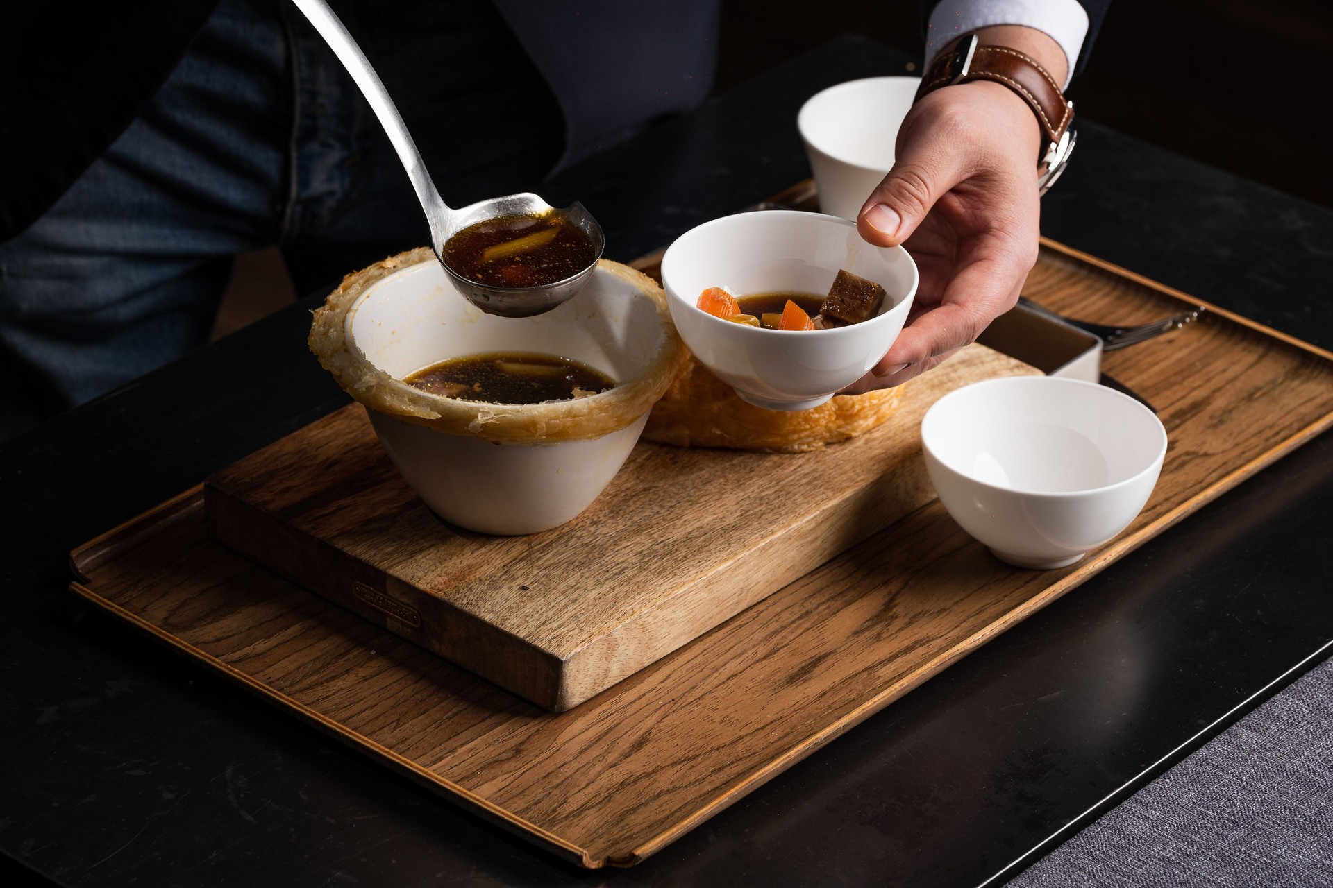 Closeup of a chef pouring a soup with carrot in a bowl