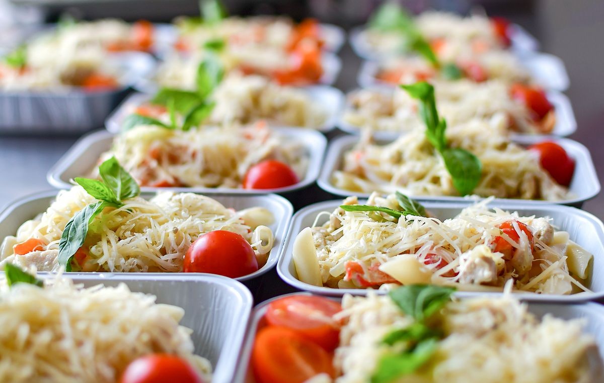 preparation of dietary dishes in the kitchen for the delivery of dietary lunch, basil, tomato cherry, cheese, pasta and chicken fillet. concept of takeaway food. selective focus